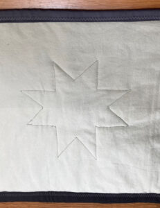 Back view, Quilting: star outline around each of the 6 full stars of the runner.